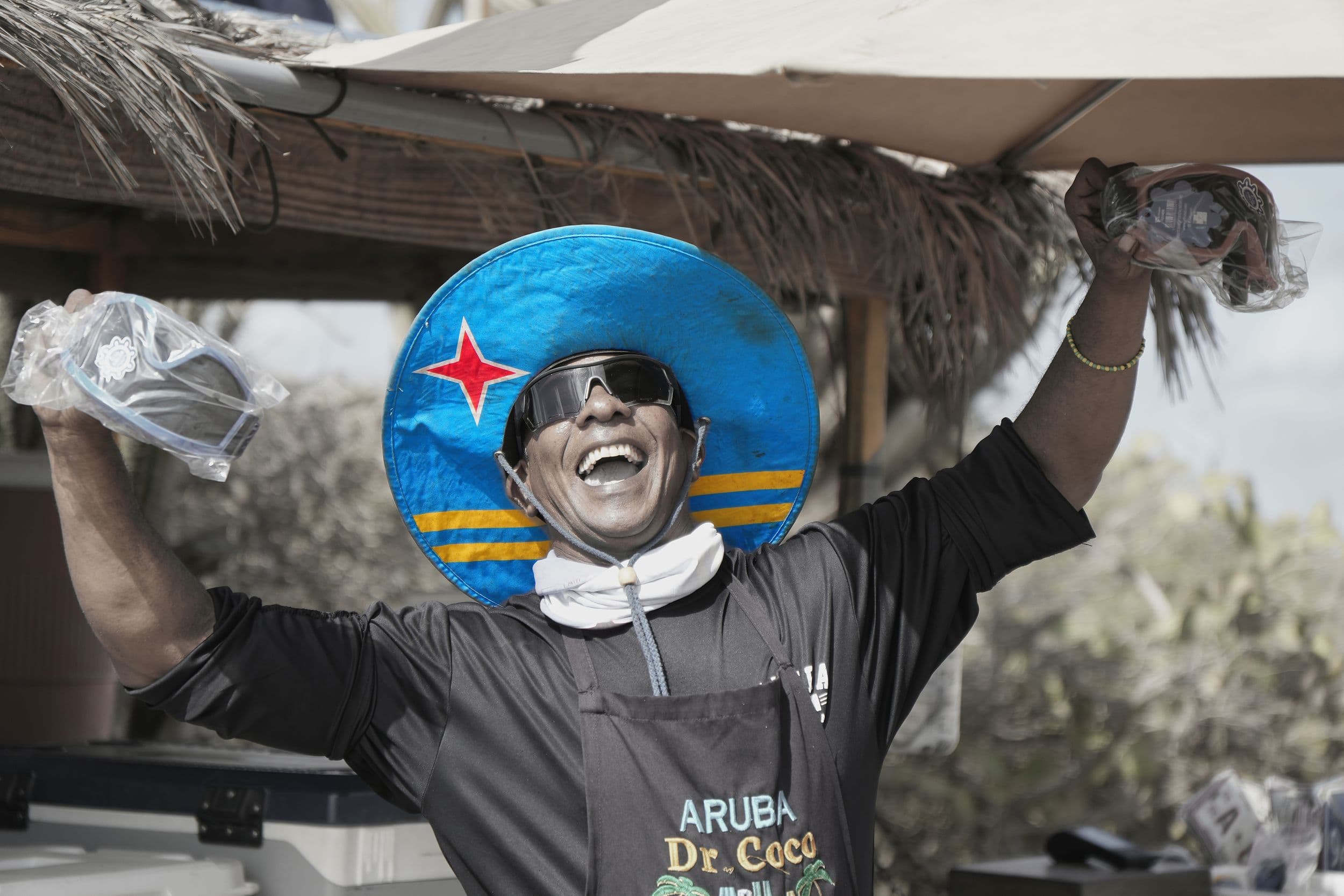 Man celebrating at outdoor event with Aruba flag hat